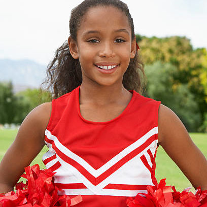 Girl cheerleader (7-9 years) standing on soccer field, portrait